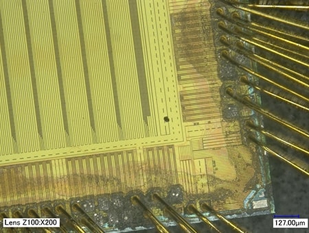 Oblast s cizorodou částicí na čipu integrovaného obvodu (200×)
